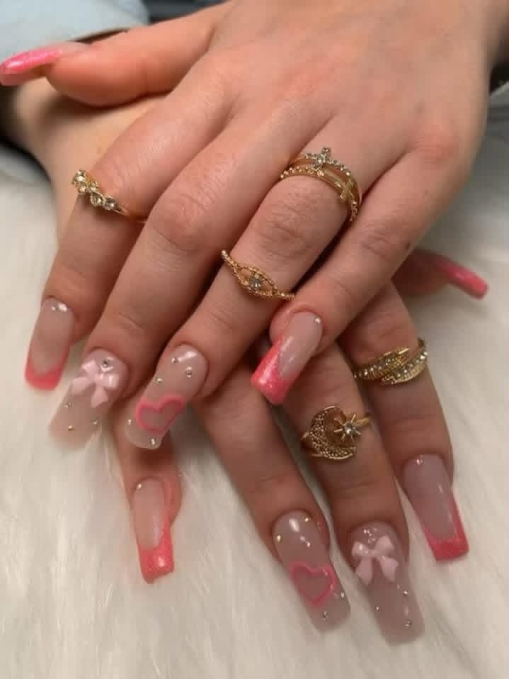 Pink French tips with heart and bow nail art and rhinestones