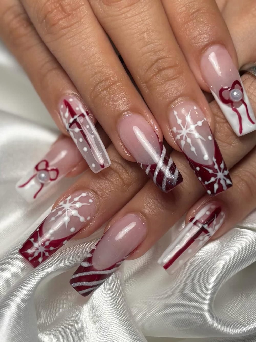 Burgundy and white holiday nail art with snowflakes and candy-cane stripes